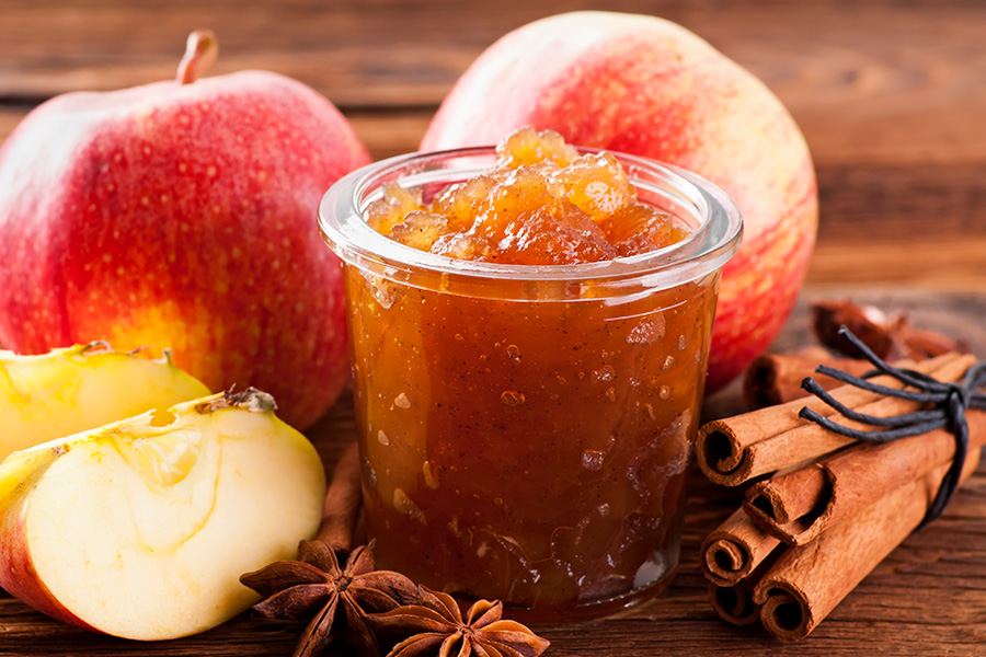 Offenes Glas mit Marmelade arrangiert mit Äpfeln, Sternanis und Zimtstangen